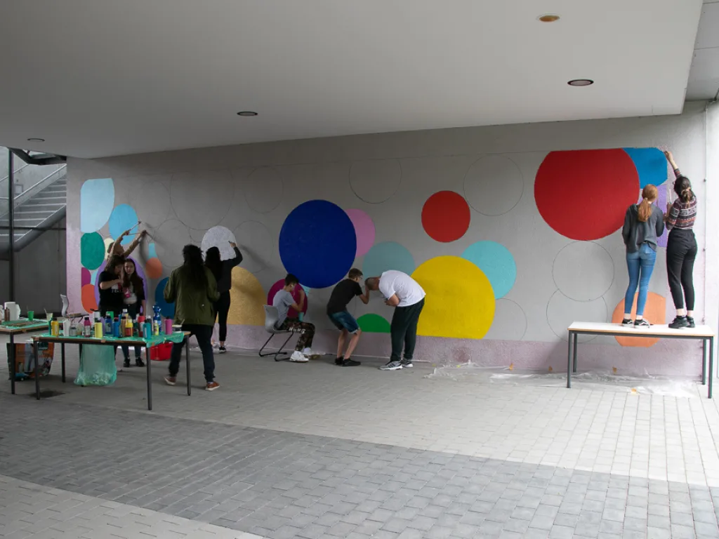Gruppe gestaltet eine Wand mit großen bunten Kreisen.